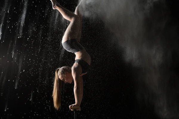 Acrobatic woman handstand on equilibr while sprinkled flour — Stock Photo, Image