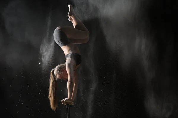 Female gymnast handstand on equilibr while sprinkled flour — Stock Photo, Image