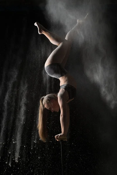 Female gymnast handstand on equilibr while sprinkled flour — Stock Photo, Image