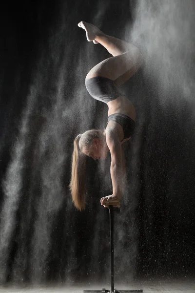 Woman gymnast handstand on equilibr while sprinkled flour — Stock Photo, Image