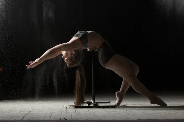 Kvinnan gör gymnastiska inslag på stativ medan beströdda mjöl — Stockfoto