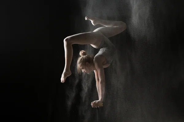 Soporte de mano de mujer flexible gimnástico en equilibrio en harina espolvoreada — Foto de Stock