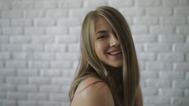 Leuke oprechte bevrijde vrouw poseren op witte bakstenen muur achtergrond — Stockvideo