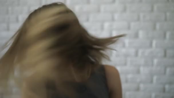 Woman fluttering her hair on white brick wall background — Stock Video