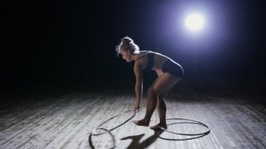 Akrobatik kadın sanatçı hula hoop karanlık sahne üzerinde döndürme