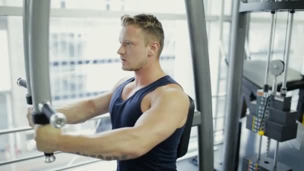 Hombre deportivo haciendo ejercicio en aparato de entrenamiento en gimnasio — Vídeos de Stock