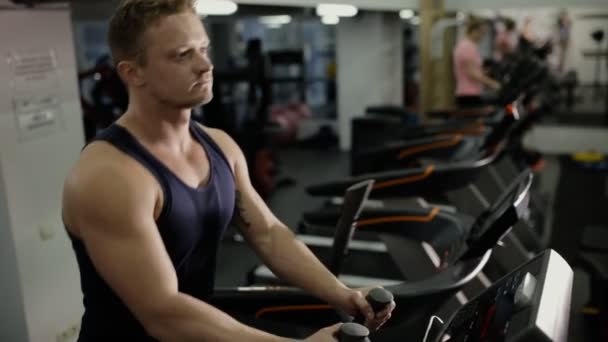 Atleta masculino haciendo ejercicio cardiovascular en el aparato de entrenamiento en el gimnasio — Vídeos de Stock