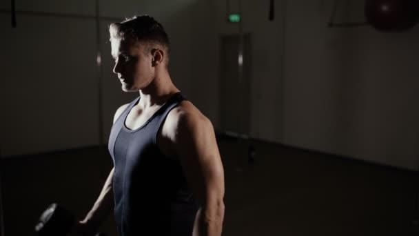 Atleta masculino bombeando bíceps con mancuerna en el gimnasio — Vídeo de stock