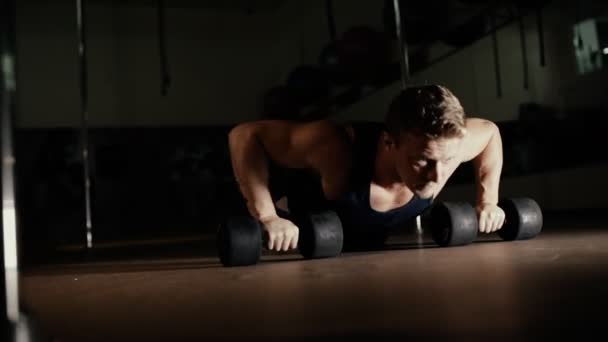 Athletic man doing push ups from dumbbells in gym — Stock Video