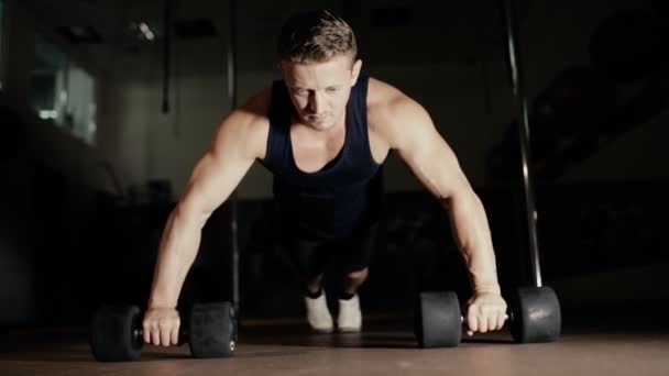 Athletic man doing push ups from dumbbells in gym — Stock Video