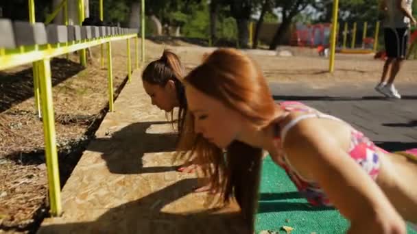 Спортсменки отжимаются на открытом воздухе на спортивной площадке — стоковое видео