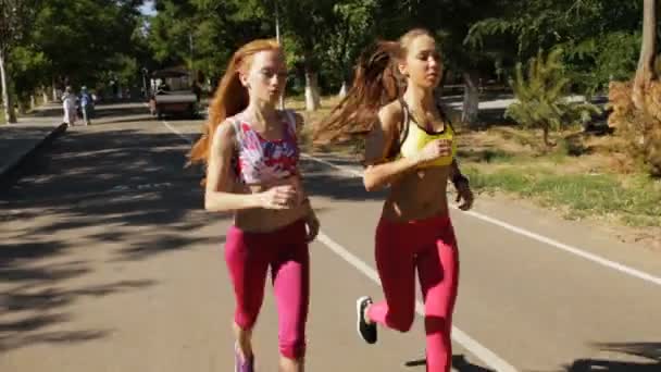 Deportivas novias trotando juntas al aire libre en el parque — Vídeo de stock