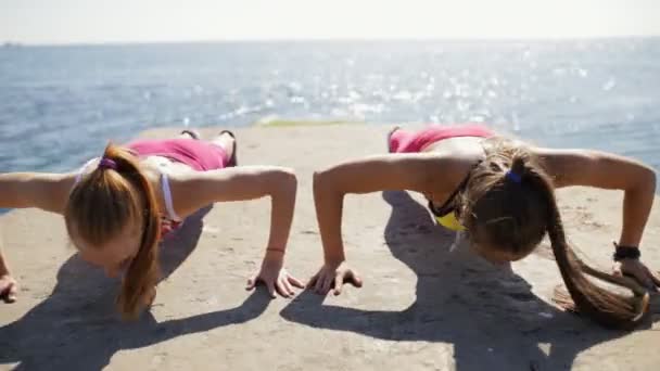 Idrottskvinnor push ups utomhus på havet piren — Stockvideo