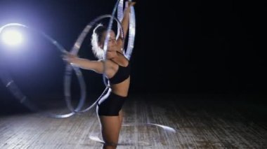 Akrobatik kadın sanatçı hula hoop karanlık sahne üzerinde döndürme
