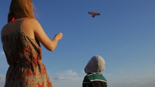 Vrouw met haar zoon greep vliegende kite bij hemelachtergrond — Stockvideo