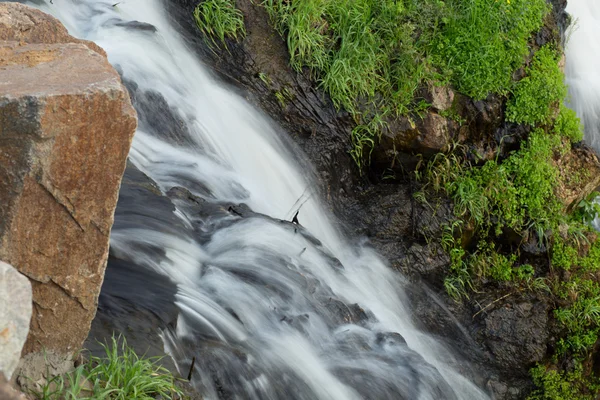 Водопад крупным планом в природе с травой и камнями . — стоковое фото