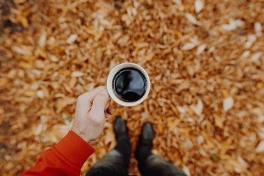 POV, sonbahar günü elinde kahve olan adam.