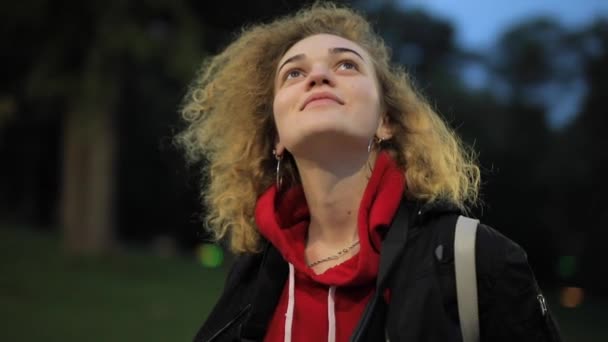 Kręcone kobieta rozgląda się w parku wieczorem — Wideo stockowe