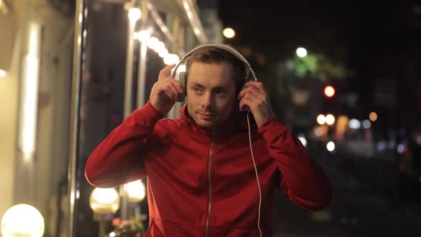 Mężczyzna nosi słuchawki w nocnym mieście — Wideo stockowe