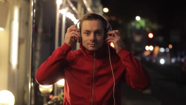 Seorang pria memakai headphone di kota malam — Stok Video