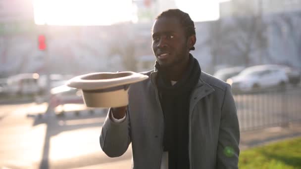 Gelukkige Afrikaanse man speelt met hoed in een stad — Stockvideo