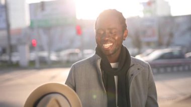 Mutlu Afrikalı adam şehir sokaklarında şapkayla oynuyor.