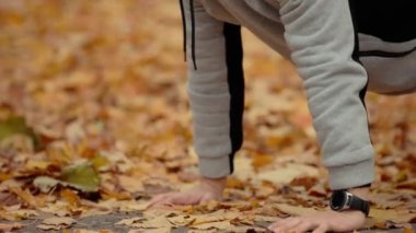 Adam sonbahar parkında dışarıda şınav çekiyor.