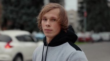 Genç bir adamın yavaş çekim videosu şehirdeki bir kameraya bakıyor.