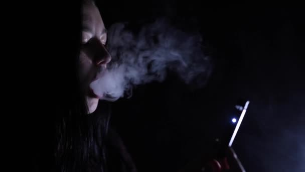 Giovane donna che fuma sigaretta elettronica al buio — Video Stock