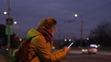 Gece kentinde telefon kullanan kadın trafiğin yakınında.