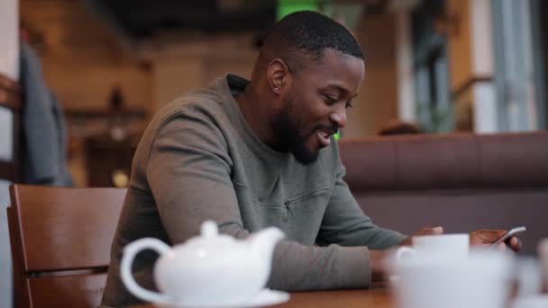 Afro-americano homem online conversando em um café — Vídeo de Stock