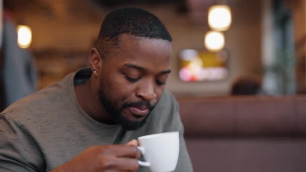 Homem afro-americano pensativo e triste bebendo chá sentado em um café — Vídeo de Stock