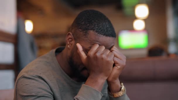 Trauriger Afroamerikaner lehnt sich mit dem Kopf an Hände — Stockvideo