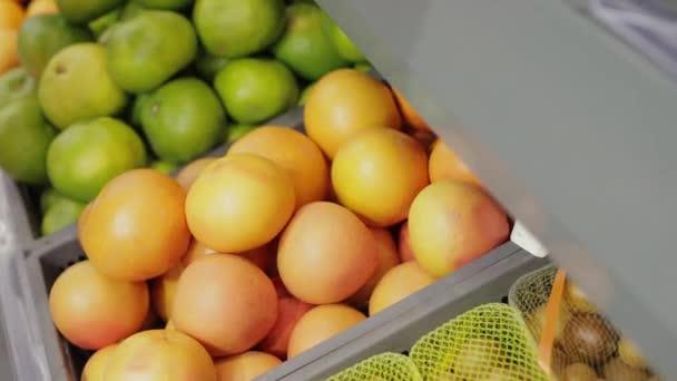 Kéz fog egy narancs gyümölcsöt a polcról a piacon — Stock videók