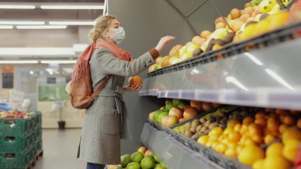 Vrouw koper kiest een sinaasappel fruit in een supermarkt — Stockvideo
