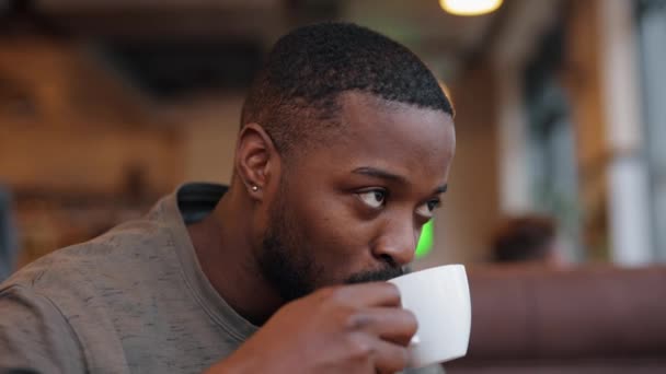 Hombre afroamericano bebiendo té sentado en un café, cámara lenta — Vídeos de Stock