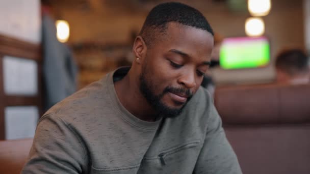 Ajattelevainen ja surullinen afroamerikkalainen mies juo teetä kahvilassa — kuvapankkivideo
