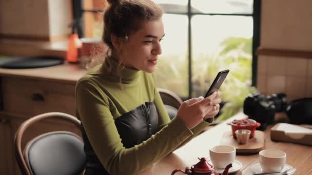 Kobieta korzystająca z telefonu komórkowego siedzi w kawiarni — Wideo stockowe