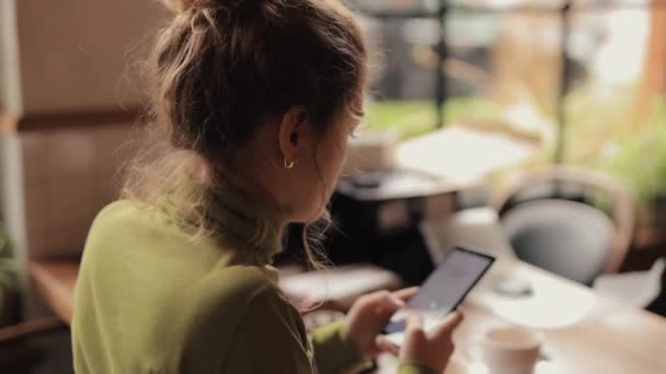 Kobieta korzystająca z telefonu komórkowego siedzi w kawiarni — Wideo stockowe