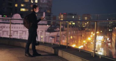 Şehir terasında akıllı telefon kullanan bir adam.
