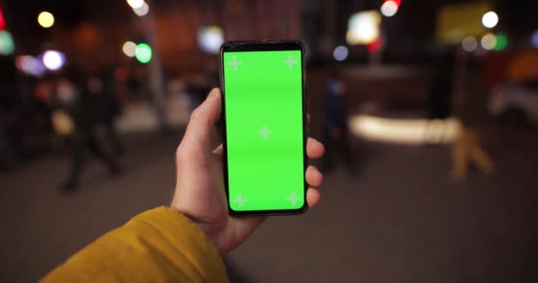 POV, męska ręka trzymająca smartfona z zielonym ekranem w nocnym mieście — Wideo stockowe
