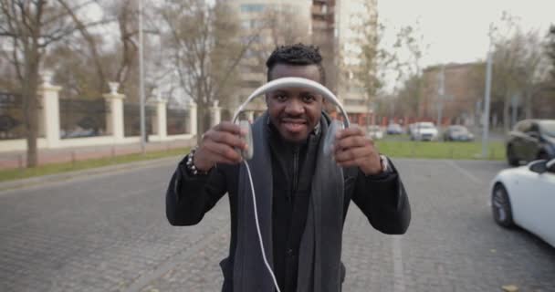Afrikansk mann setter på hodetelefoner i sakte film – stockvideo