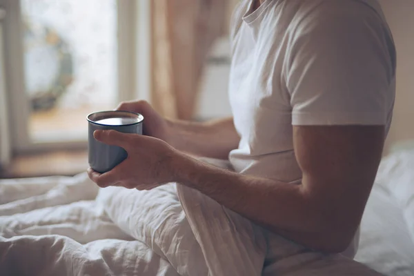 Cortado tiro de homem bebe chá pela manhã sentado em uma cama — Fotografia de Stock