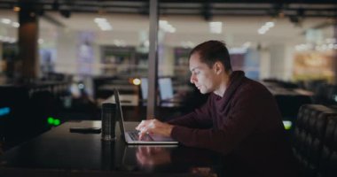 Bir gece kafesinde dizüstü bilgisayarla çalışan adam.