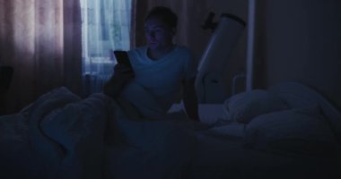 Yatakta cep telefonu kullanan bir adam, mavi ışık.