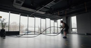 Spor salonunda ip egzersizi yapan bir adam.