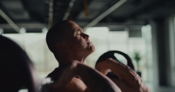 Homme athlétique poussant haltère dans la salle de gym, au ralenti — Video