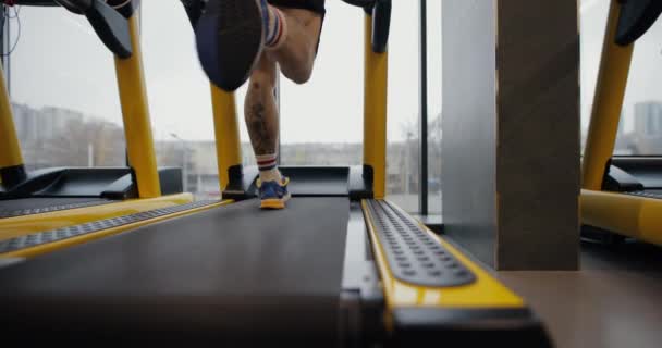 Nohy muže běžícího na běžícím pásu v tělocvičně, zpomalený pohyb — Stock video
