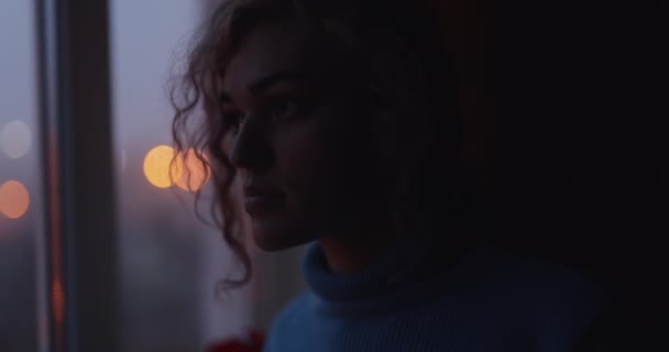Mulher olhando através da janela na rua da noite — Vídeo de Stock