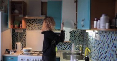 Kadın mutfaktaki raftan bir tabak al.